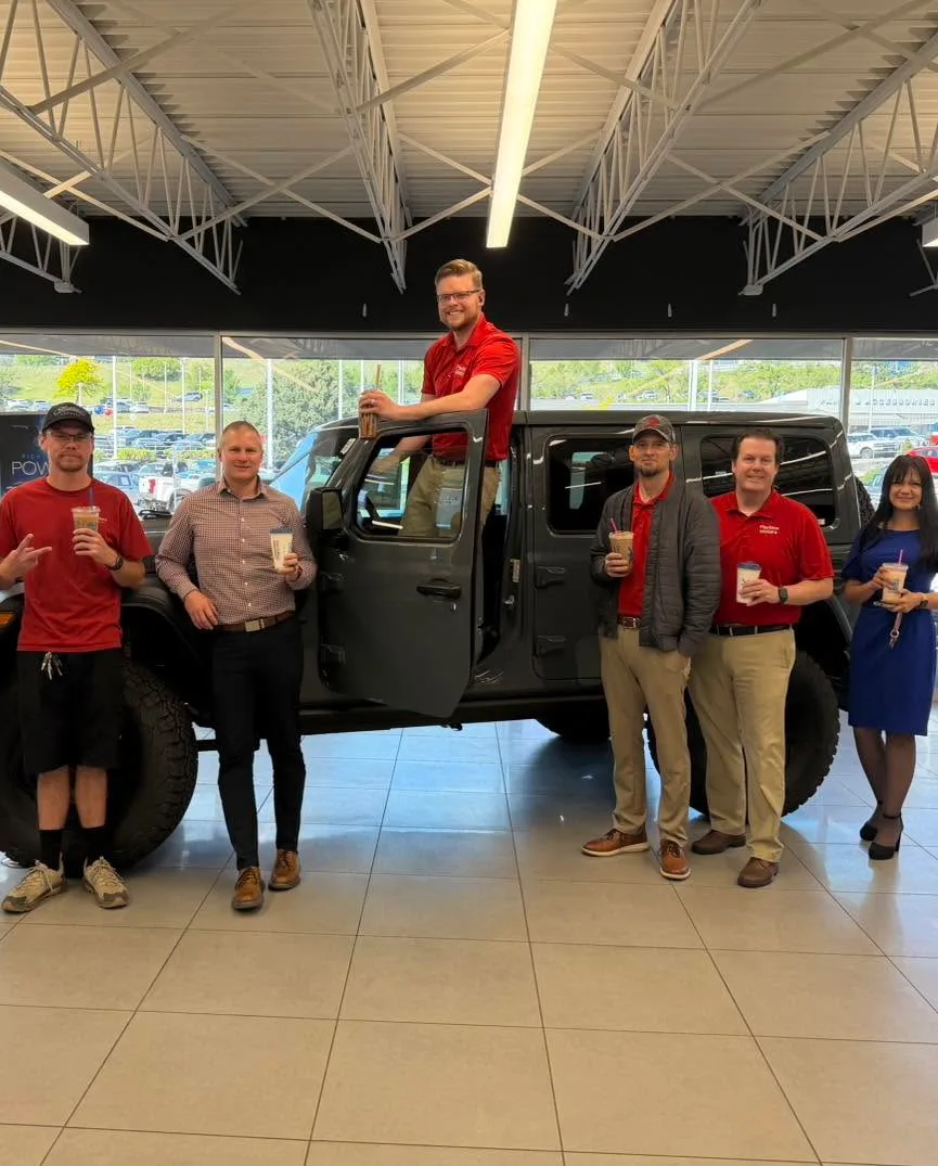 Dealership staff gathered around a vehicle inside the showroom.